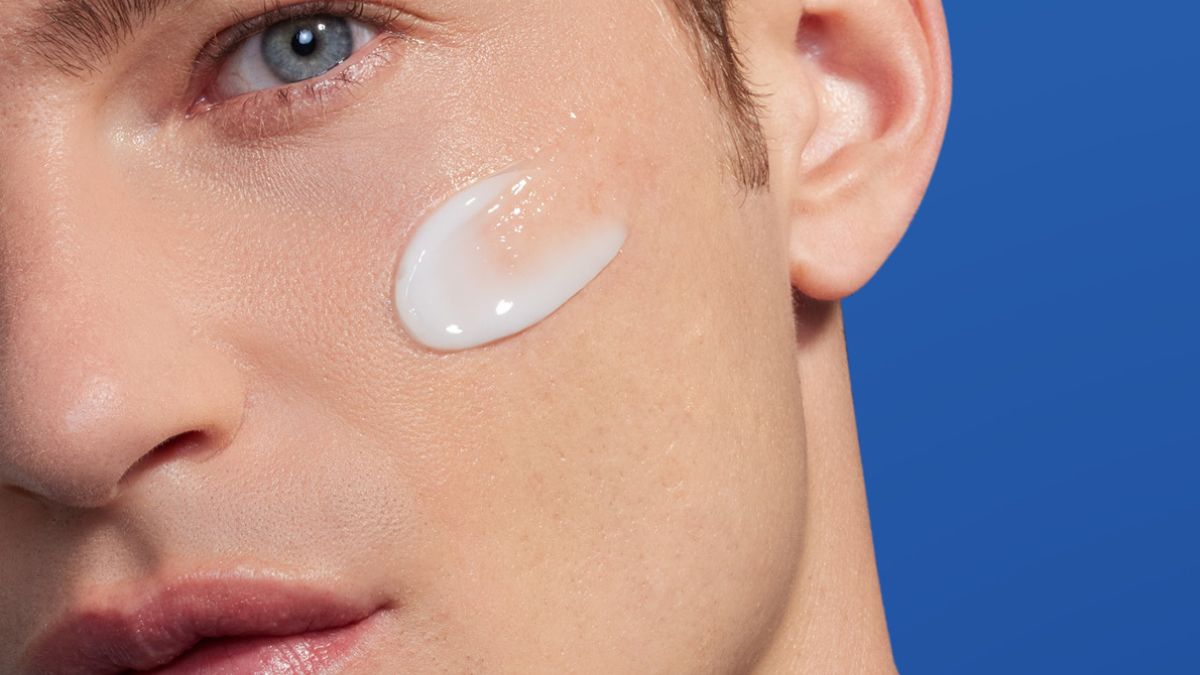 A man applying summer face cream to his skin.